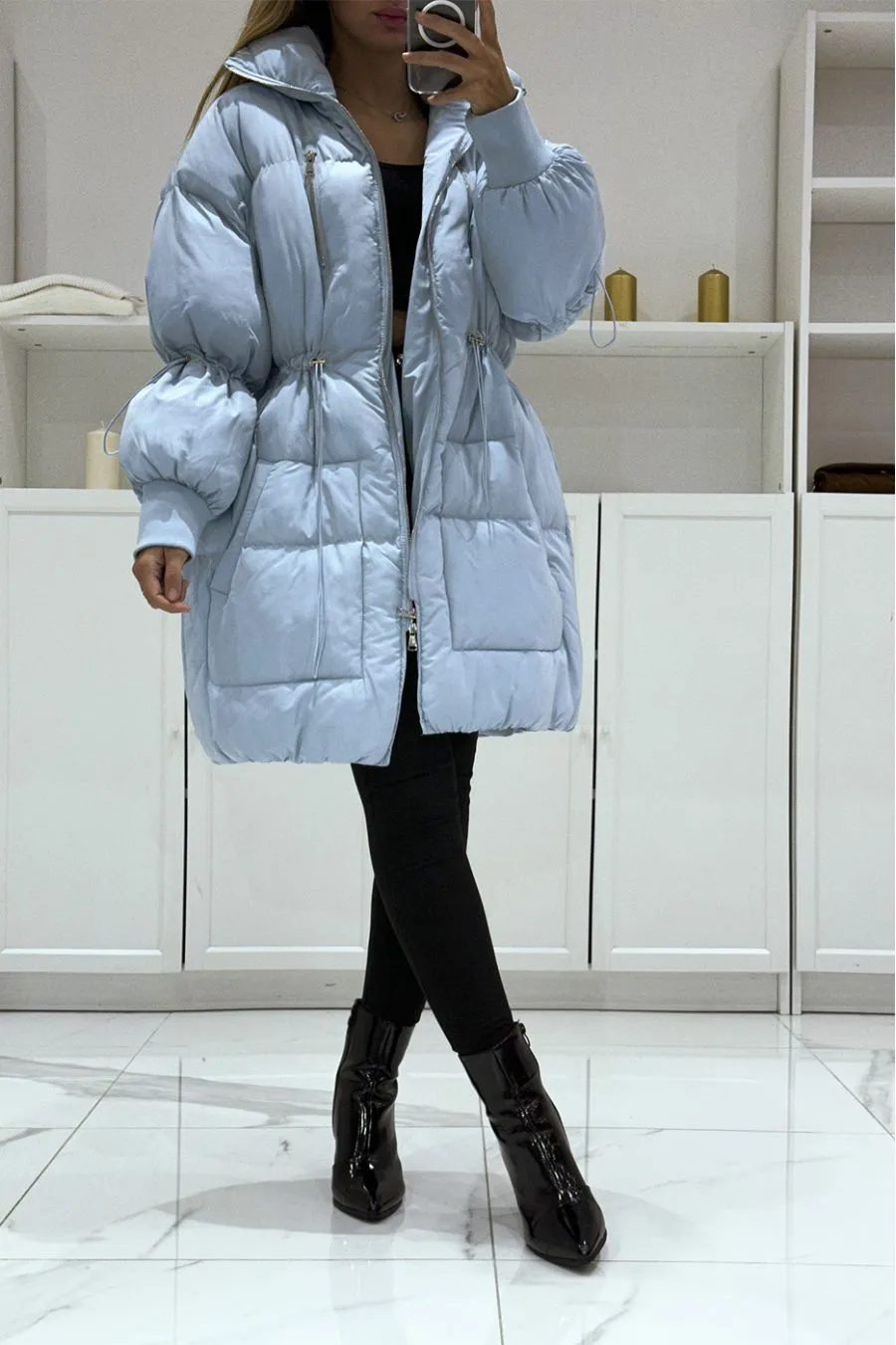 Turquoise puffer coat with oversized collar and drawstring closure.